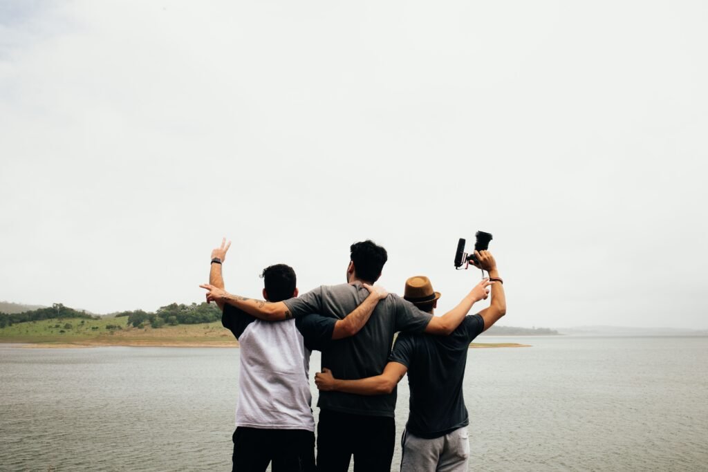 Three friends embracing by a lake, representing the lasting value of social health and genuine friendship
