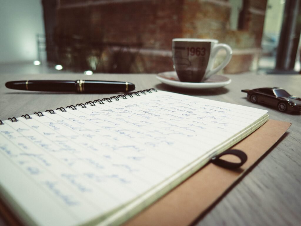 Handwritten notebook with pen and coffee, representing how to build your own 27 for 2027 goal list