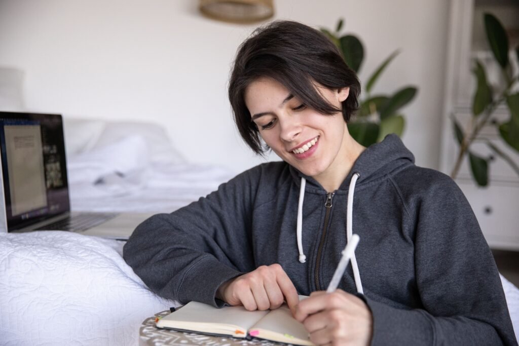 Smiling woman happily journaling at home, showing the joyful side of low-pressure goal setting