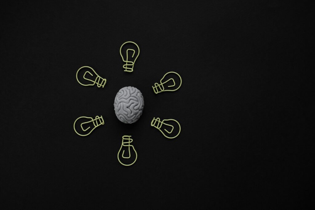 Brain surrounded by lightbulb shapes, representing the neuroscience behind how tiny habits form and stick