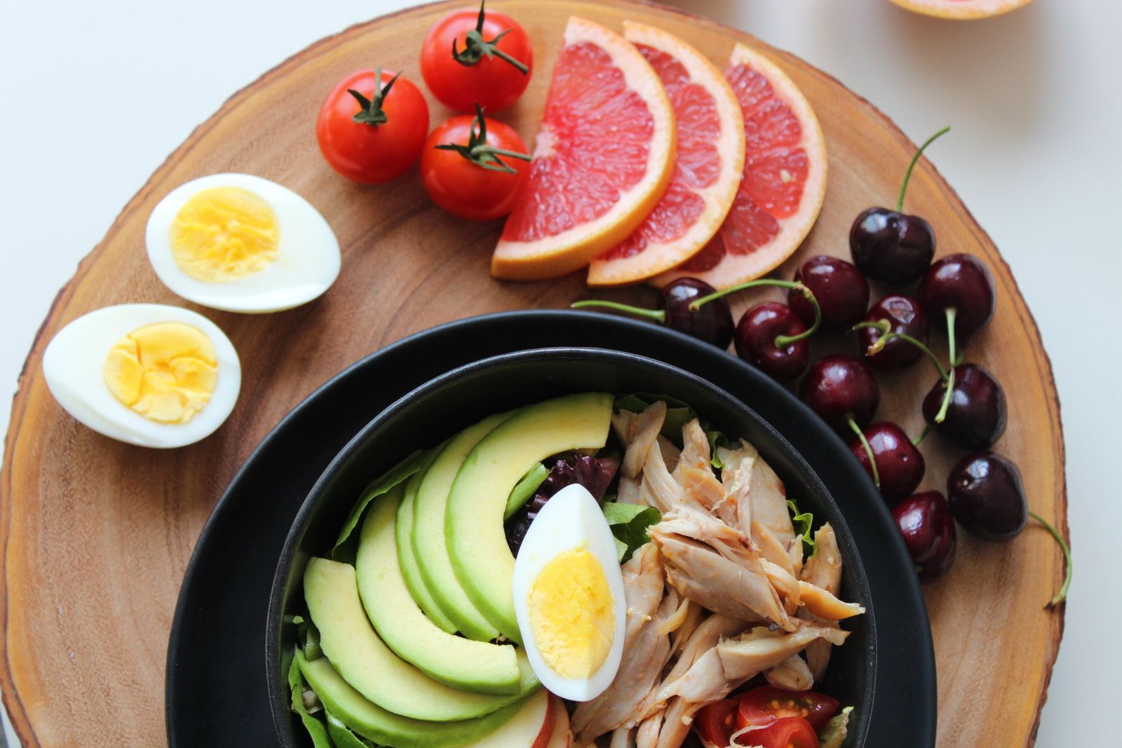 Colorful bowl of fresh, whole foods including avocado, eggs, and fruit, representing gut-healthy nutrition