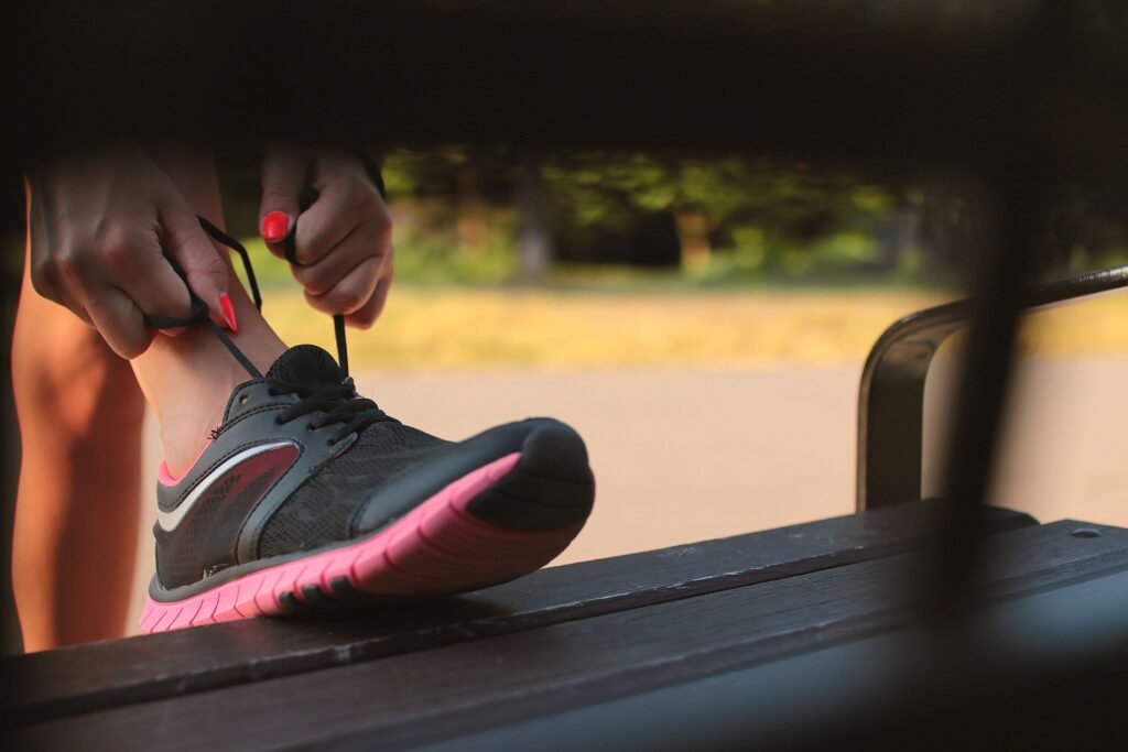 Person tying running shoes outdoors, representing the micro habit of just putting on workout shoes