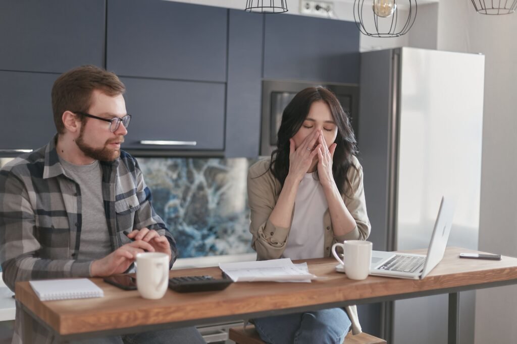Exhausted woman covering her face at a work desk, illustrating the hidden cost of chronic sleep deprivation