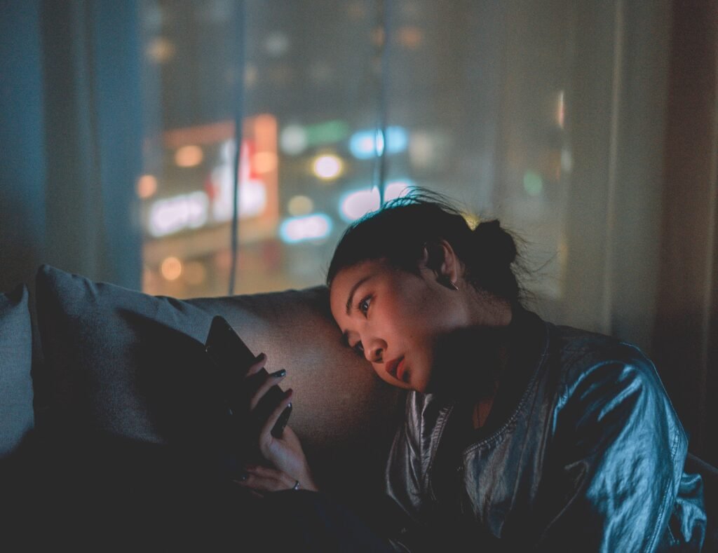 Woman alone with phone at night symbolizing social disconnection and loneliness