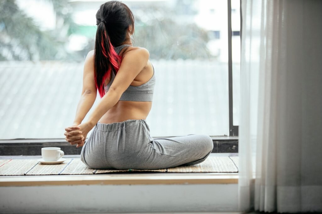 Woman stretching peacefully by a window with coffee, symbolizing the restorative benefits of good sleep