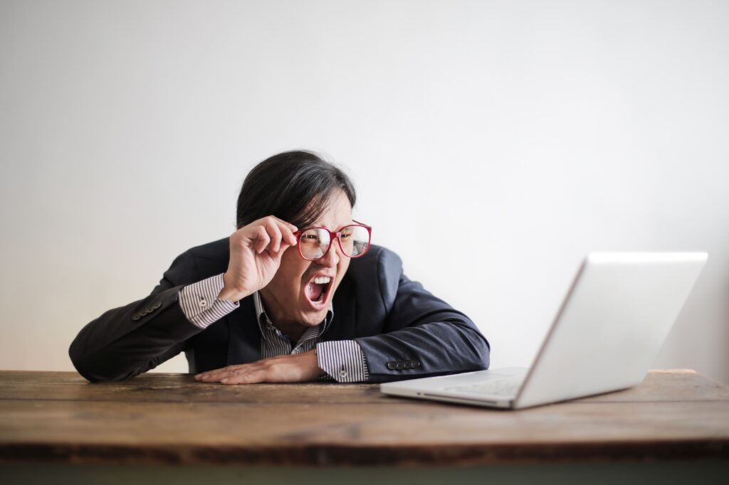 Man having an intense reaction at his laptop, showing the brain's fight-or-flight response