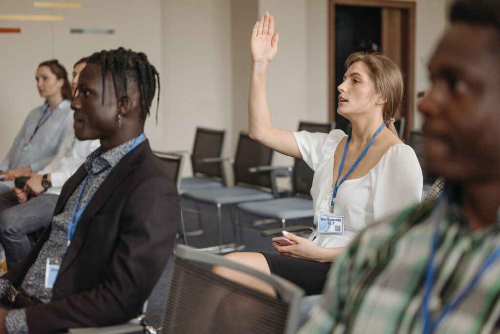 Woman raising her hand to ask a thoughtful question during a group discussion