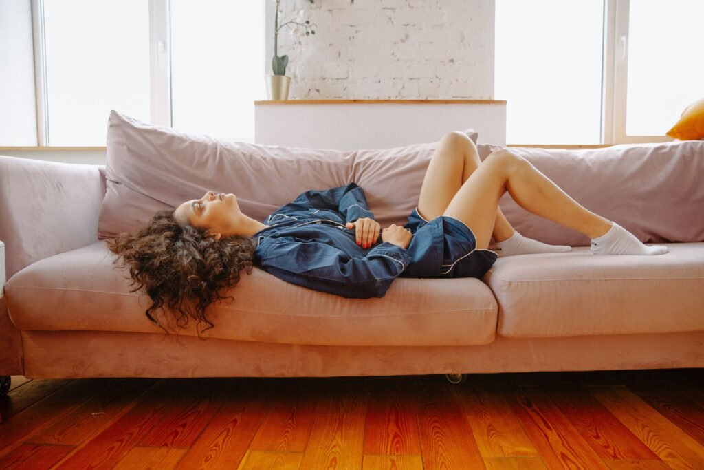 Woman relaxing on a couch with hand on her stomach, reflecting the connection between gut health and mood