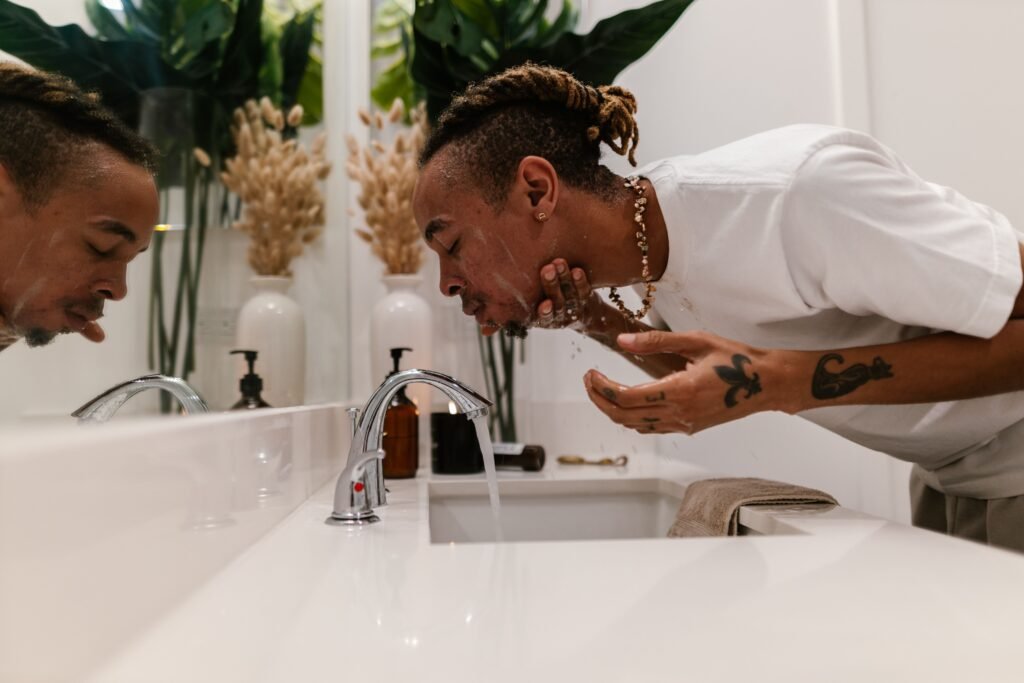 Man splashing cold water on his face at a bathroom sink, illustrating cold exposure as a nervous system regulation technique