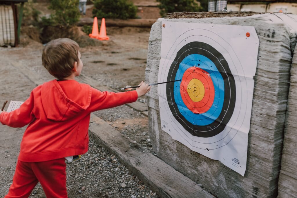 Child aiming an arrow at a target, representing focused effort toward achieving a specific goal