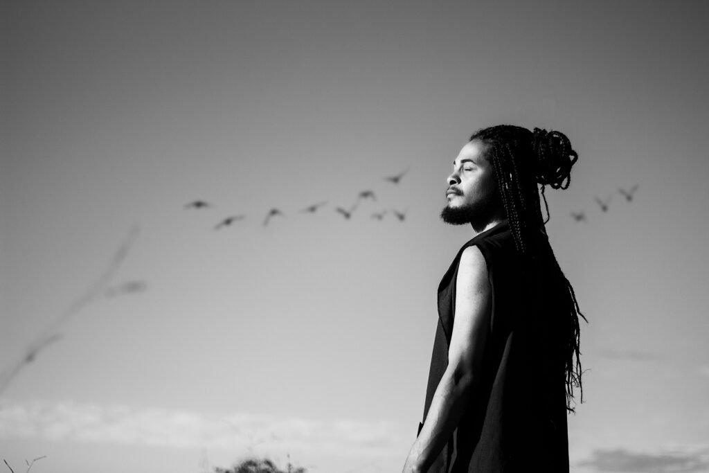 Person standing calmly with eyes closed as birds fly by, representing peace 

