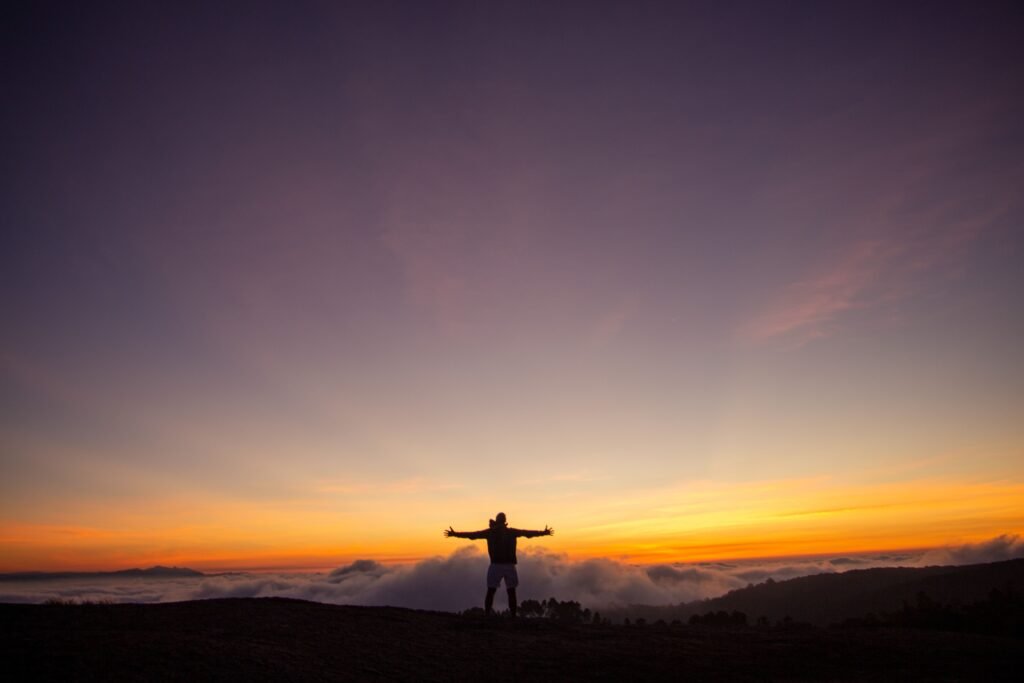 Person celebrating on mountain at sunrise representing mastering time and life