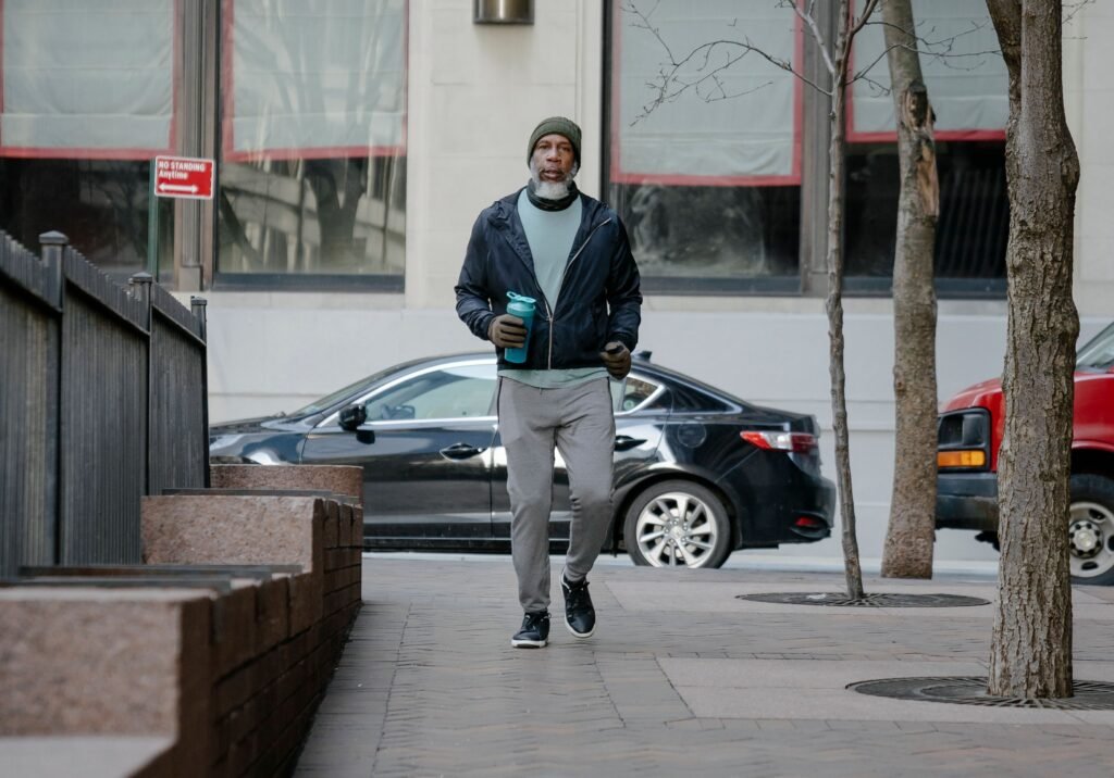 Man walking outdoors in casual workout clothes carrying a water bottle