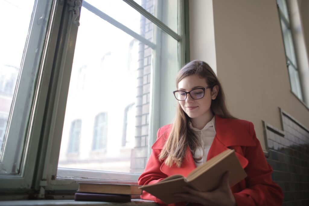 Woman reading a book by the window - building a daily reading habit
