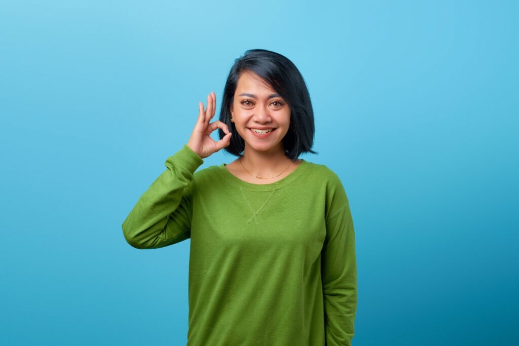 Woman smiling and making an OK hand gesture, representing that it's okay to slip up occasionally when breaking a habit